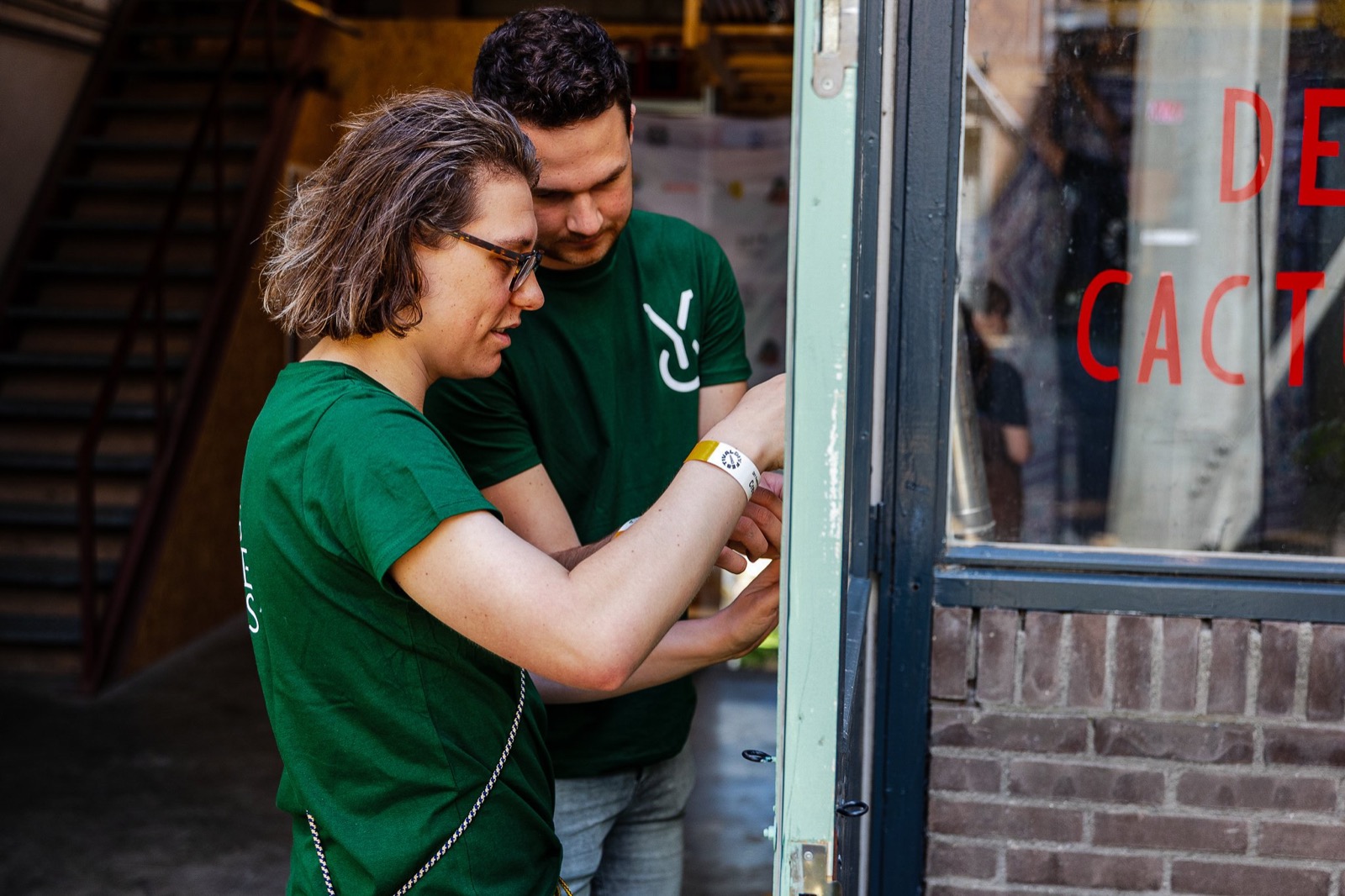 Twee Young Changemakers bevestigen een polsbandje bij een evenement
